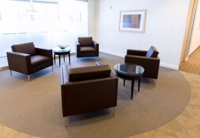 Communal lounge area with comfortable brown leather armchairs and circular coffee tables.
