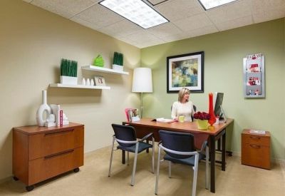 Private office suite with a wooden desk, green accent wall, and decorative shelving.