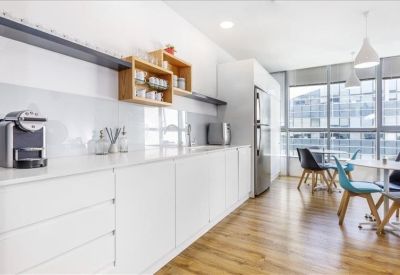 White minimalist kitchen and breakout area with light wood flooring.