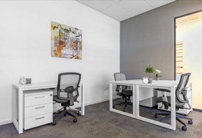 Private office with white desks and a colourful wall painting.