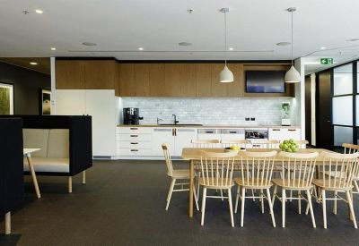 Kitchen and dining area with a long wooden table, light-colored chairs, and marble splashback.
