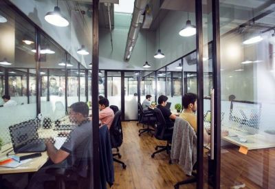 Glass-walled private office suites with individuals working at desks.