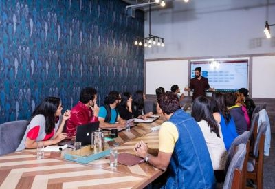 Professional meeting room featuring a long herringbone wood table and a digital presentation screen.