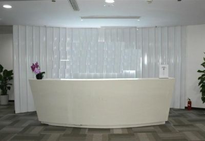 Sleek minimalist reception desk with a white curved front and a textured feature wall.