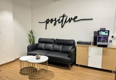 Communal lounge area with a black leather sofa and 'positive' wall art.