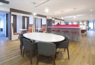 Communal breakout area featuring an oval dining table, wooden floors, and a modern bar counter.