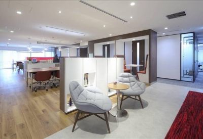 Lounge area with plush grey armchairs, a small side table, and a red feature rug.
