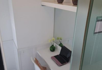 Compact private office nook with white desk, potted plants, and shelving.