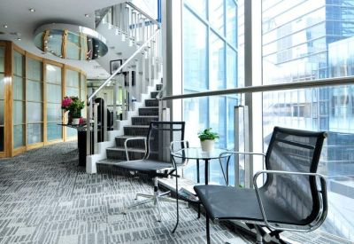 Breakout area with mesh chairs and a small table next to a staircase and large windows.