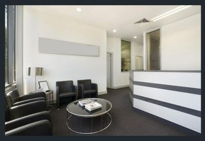 Modern reception area with black leather armchairs and a sleek curved desk.