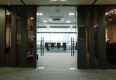 Sleek glass entrance doors leading to a modern office reception area.