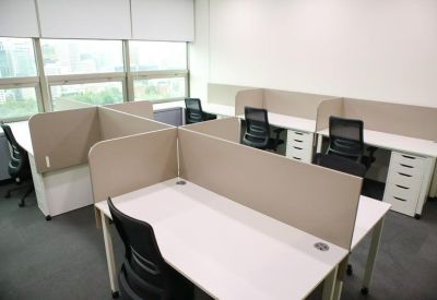 Open-plan office area with four-person desk clusters and privacy partitions.
