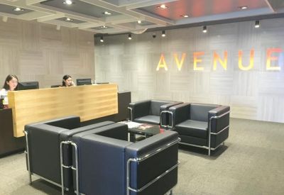 Bright reception area with wooden desk, leather armchairs, and illuminated signage on a textured wall.