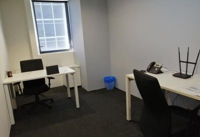 Two-person internal office suite with white desks, black chairs, and a view of a window.