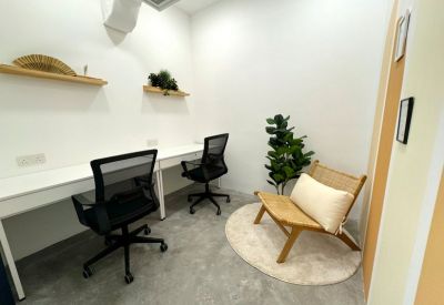 Private office with two black mesh chairs, white desks, and a woven lounge chair.
