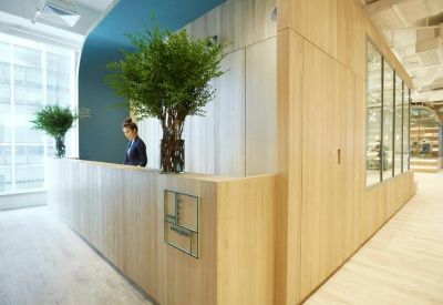 Elegant wood-paneled reception desk with large leafy plants and soft lighting.