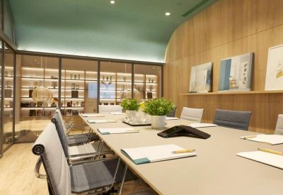 Modern conference room with a long white table and light wood wall paneling.