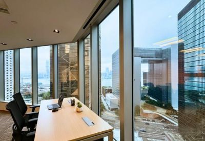 Private office with a wood desk and floor-to-ceiling windows overlooking city skyscrapers.
