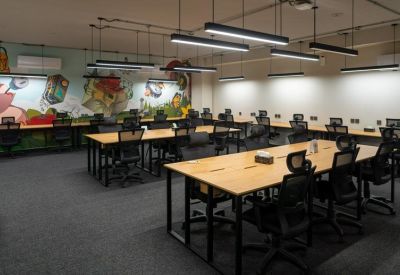 Wide open-plan workspace with rows of desks and a vibrant wall mural.