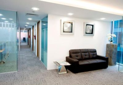Waiting area with a dark leather sofa and stylish wall art.