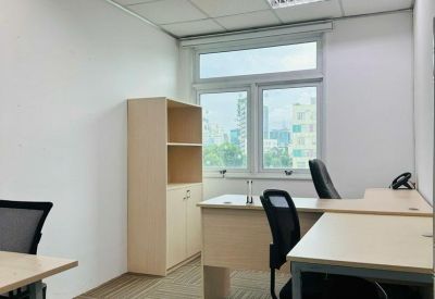 Bright private office featuring light wood desks, ergonomic black chairs, and a tall bookshelf.