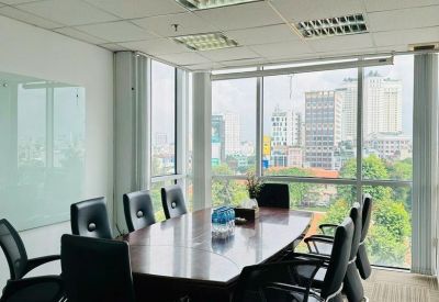 Spacious boardroom with a long wooden table, black leather chairs, and panoramic city views.