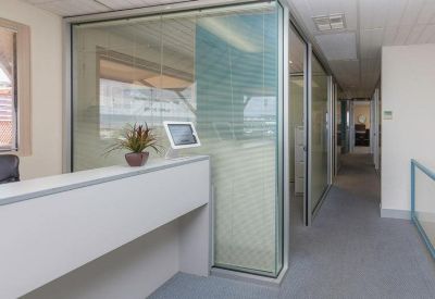 Bright reception desk with glass partitions and a indoor plant.