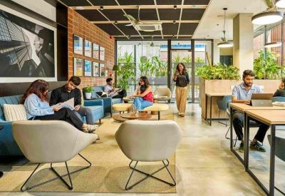 Vibrant communal lounge with blue sofas, modern armchairs, and brick accent walls.