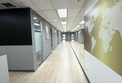 Long office corridor with a gold world map mural and recessed ceiling lights.