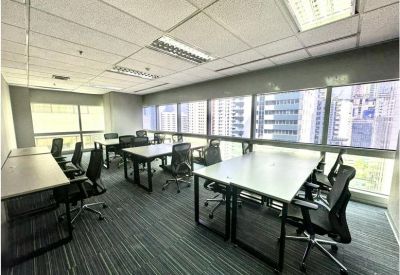 Spacious open-plan office with multiple workstations and large windows overlooking the city.