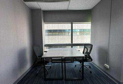 Internal two-person office suite with a simple desk and view of adjacent buildings.