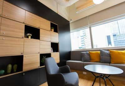 Modern breakout area with a modular sofa, colorful yellow cushions, and a wooden storage wall.