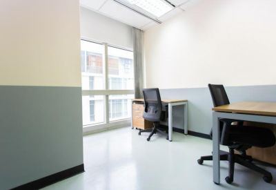 Private office space featuring two wooden desks, black mesh chairs, and a large window.