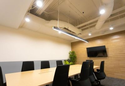 Meeting room with a long wooden table, black ergonomic chairs, and a wood-paneled feature wall.