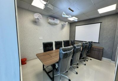 Large conference room featuring a wooden table, black chairs, and a presentation screen.
