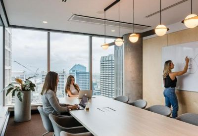 Glass-walled meeting room with a long wooden table and designer pendant lighting overlooking the city.