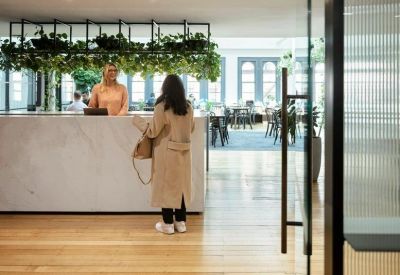 Polished marble reception desk with a lush green plant installation above.