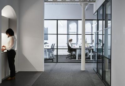Modern office interior with glass partitioning and white structural columns.