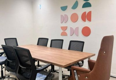 Modern meeting room with a wooden table, ergonomic chairs, and colorful geometric wall art.