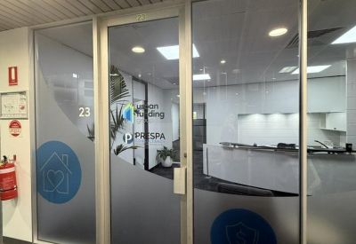 Branded glass entrance doors featuring frosted graphics and a view into the reception area.