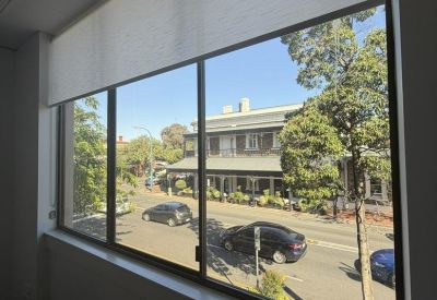 Large window view looking out onto a street with historic buildings and greenery.