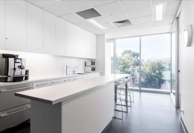 Clean communal kitchen with a white breakfast bar and professional espresso machine.