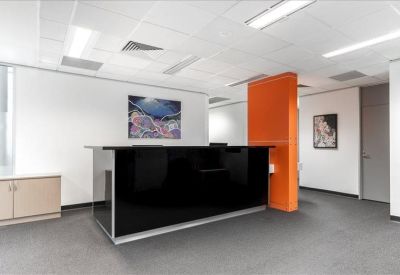 Reception area featuring a sleek black front desk and a vibrant orange feature wall.