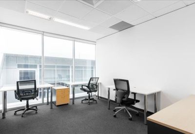 Bright three-person office suite with large windows and mesh ergonomic chairs.