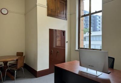 Office interior featuring a vintage-style vault door and a round timber meeting table.