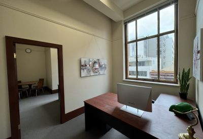 L-shaped wooden desk with a green banker lamp and views of the city.