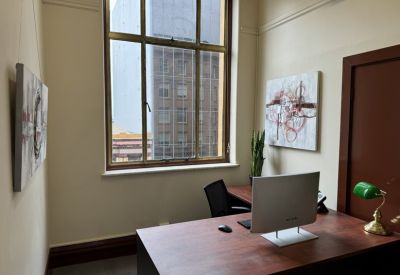 Bright workspace with abstract wall art, potted snake plant, and large multi-pane window.