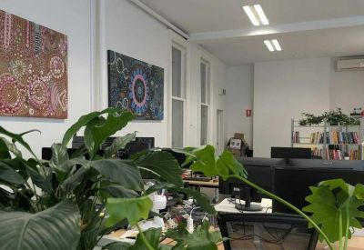 Creative office space with vibrant indigenous wall art and large green indoor plants.