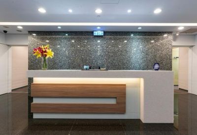 Modern reception area featuring a white and wood desk against a dark marble feature wall.