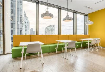 Communal break area with built-in green and yellow bench seating alongside small tables.